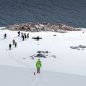 People hiking down a snowy mountain towards the water