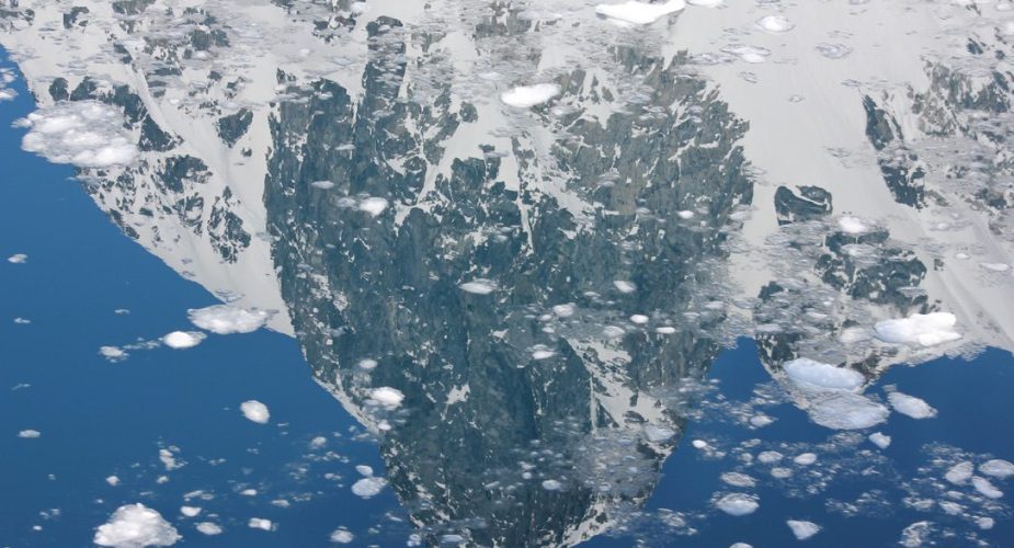 The reflection of a mountain in the icy waters of the Arctic Ocean in Antarctica
