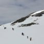 People hiking up a snowy mountain in a line.