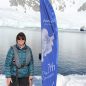 Wendy posing next to a flag in Antarctica